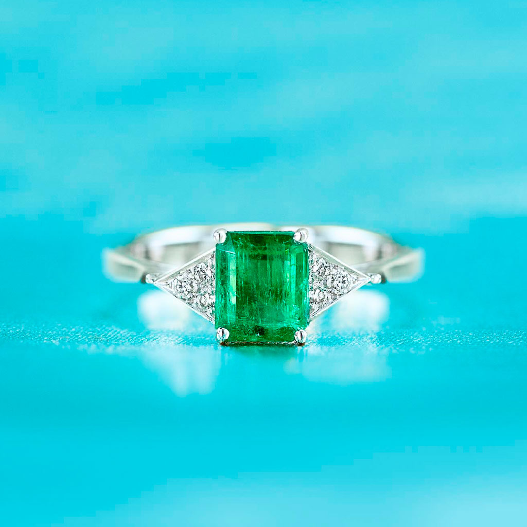 Anel com esmeralda central, com diamantes laterais